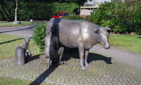 Eine Arbeit aus Bronze die eine Kuh, die Melkerin und ein Kind zeigt.